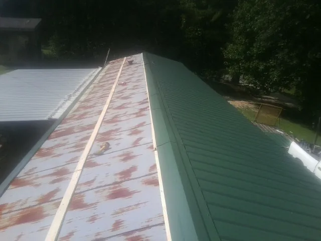 Old rusted panels beside newly installed green metal roofing — Wind Damage Roof Repair by Roofing Brothers in Waupaca