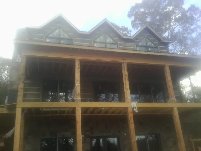 Dormers and porch framing on a large log home under construction — Roof Coating work by our crew in Waupaca