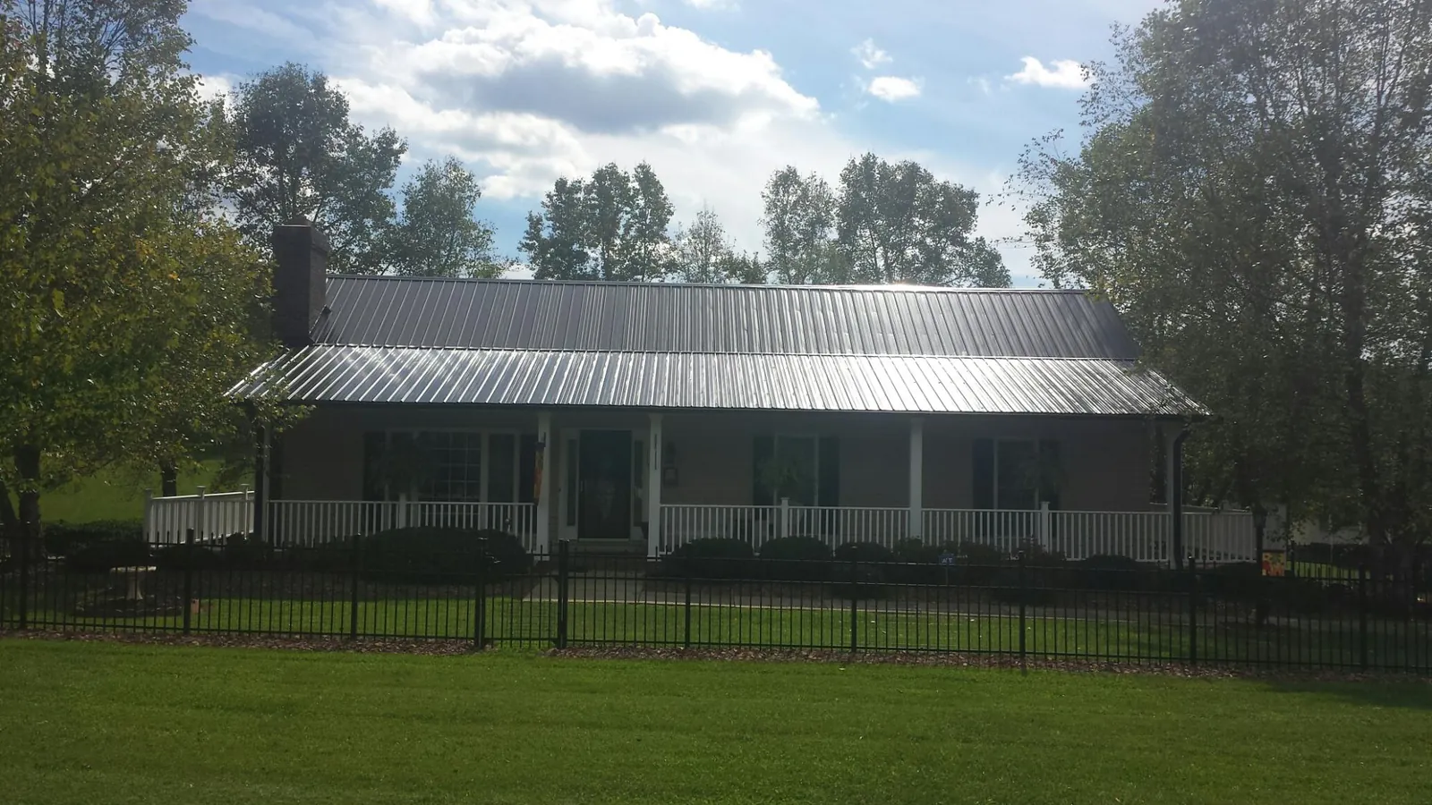 Gray metal roof on a brick ranch with a full width front porch — Gutter Guard Installation work by our crew in Waupaca