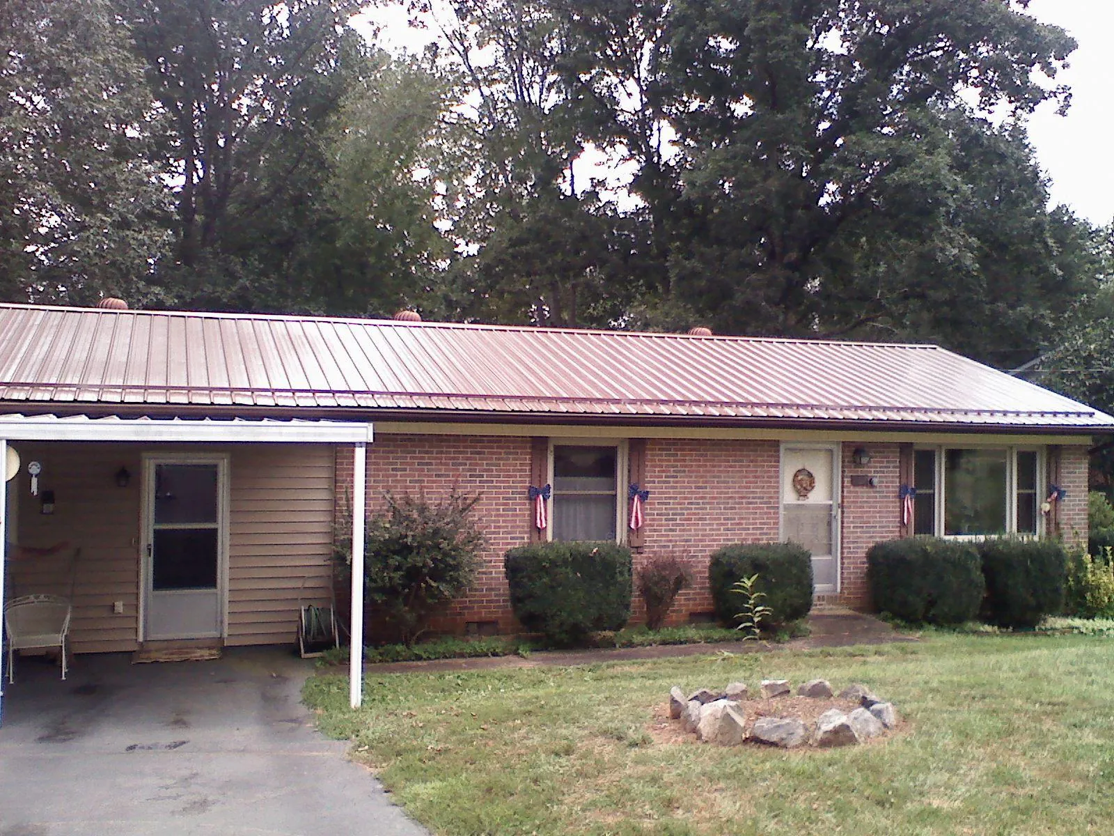 Bronze metal roof and carport on a brick ranch home — Roof Repair work by our crew in Waupaca