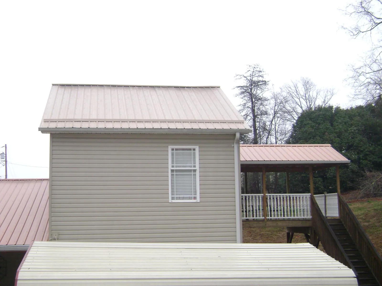 Tan metal roofs on a two story addition and attached porch, from a Roof Replacement job in Waupaca